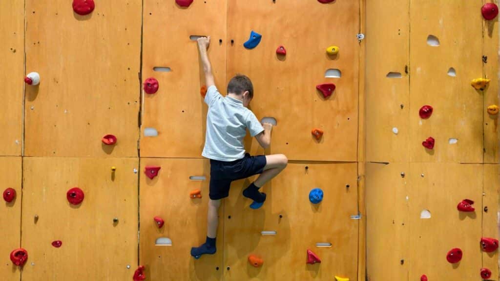 Bambino che utilizza una parete d'arrampicata attrezzata per migliorare la prassia e l'organizzazione del movimento nello spazio