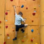 Bambino che utilizza una parete d'arrampicata attrezzata per migliorare la prassia e l'organizzazione del movimento nello spazio