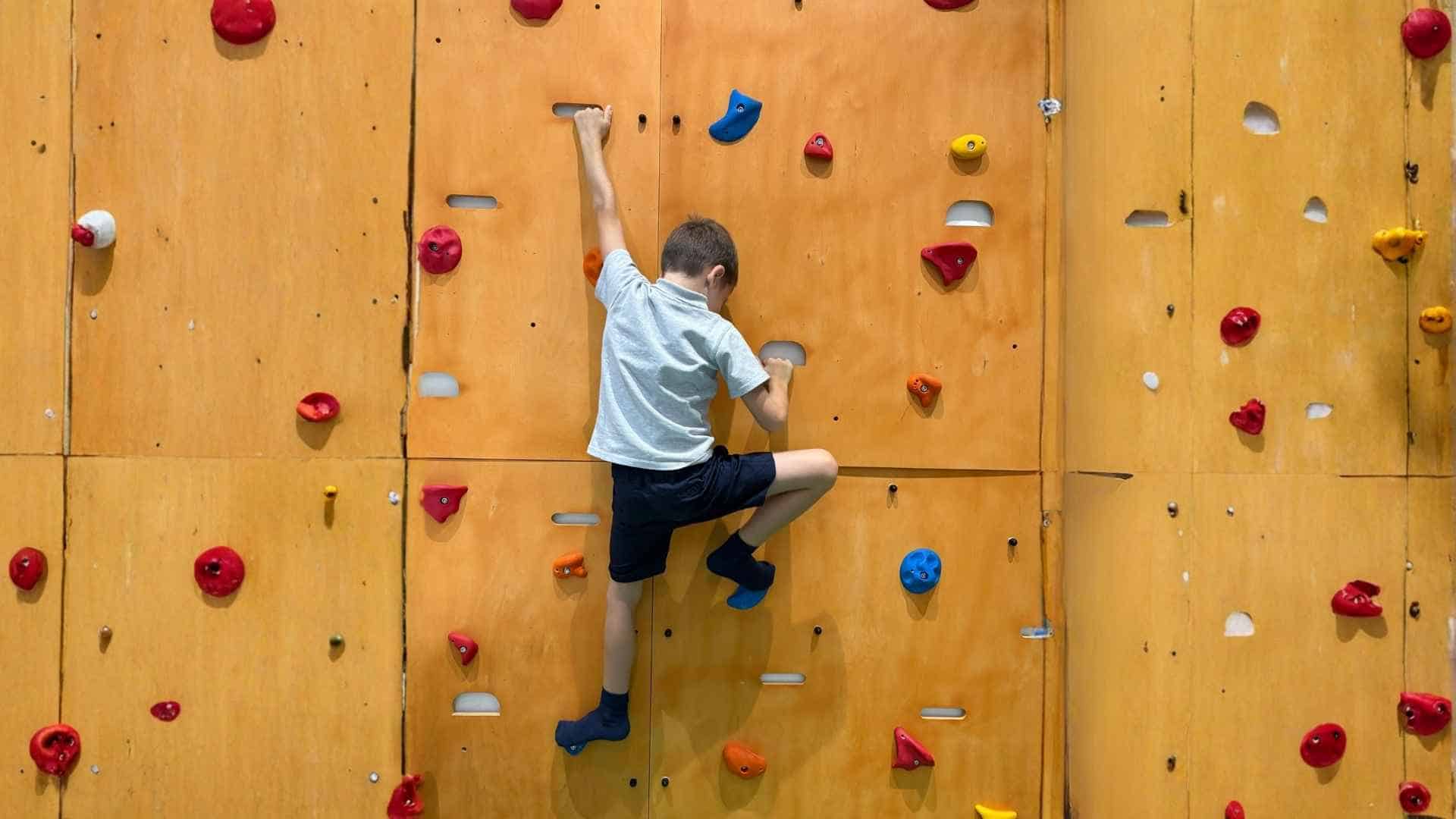 Bambino che utilizza una parete d'arrampicata attrezzata per migliorare la prassia e l'organizzazione del movimento nello spazio