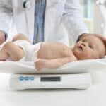 Neonato durante una visita di controllo sulla bilancia pediatrica per il calendario visite del primo anno a Paradiso, Svizzera