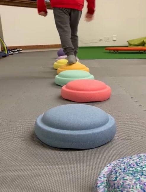 Bambino che esegue un esercizio di equilibrio su semisfere colorate in una stanza di integrazione sensoriale presso il centro di ergoterapia a Paradiso