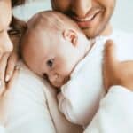 Genitori che sorreggono con cura il capo e la schiena di un neonato, illustrando le buone pratiche di sicurezza suggerite dal pediatra a Paradiso