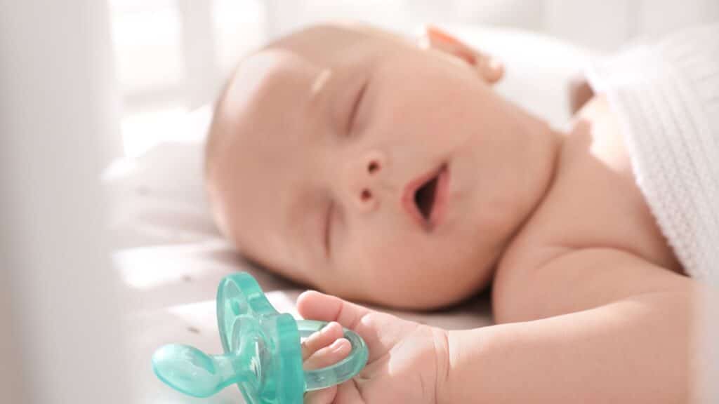 bambino che dorme serenamente con in mano il suo ciuccio