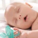 bambino che dorme serenamente con in mano il suo ciuccio